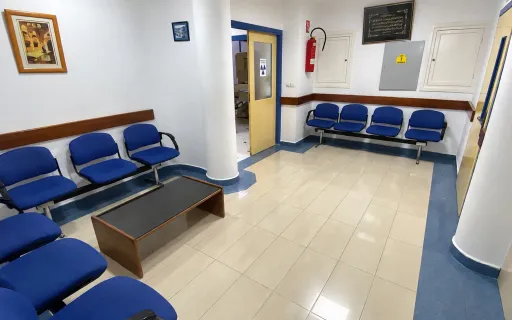 Salle d’attente du centre avec des sièges bleus et une porte ouverte vers une salle d’examen.